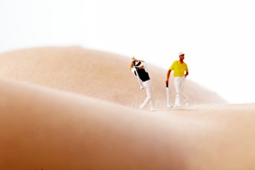 Miniature Figures playing golf on naked woman body
