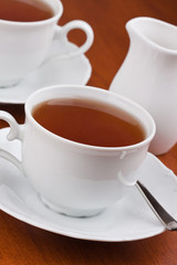 Black tea in mugs with saucers
