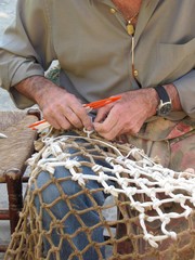 PESCADOR REPARANDO LAS REDES DE PESCA