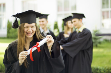 A graduate holding a diploma and smiling