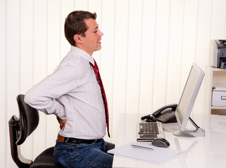 Mann im Büro bei Computer und Rücken Schmerzen