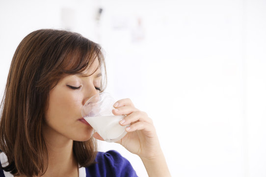 young woman drinking milk on white background