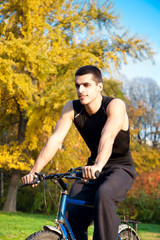 Young man ride a bike in autumn park