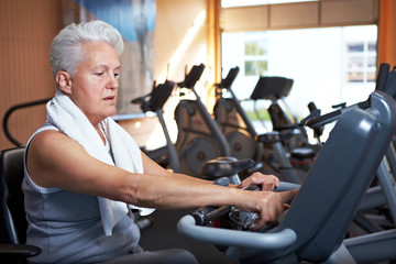 Seniorin fährt Rad im Fitnesscenter