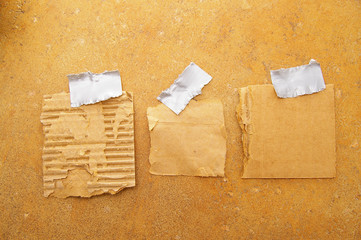 three pieces of torn grunge paper, taped to a wall