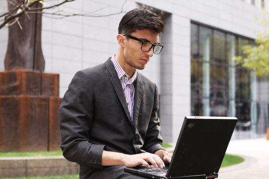 Young Man Using Laptop In The Park