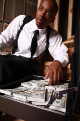 Young stylish man with a briefcase of cash and a gun