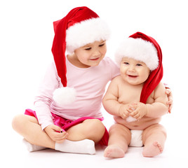 Two children wearing red Christmas caps and smile