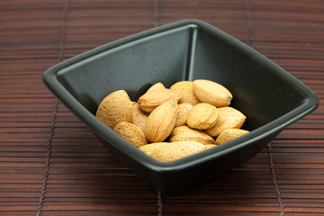 almonds in a bowl on a bamboo mat