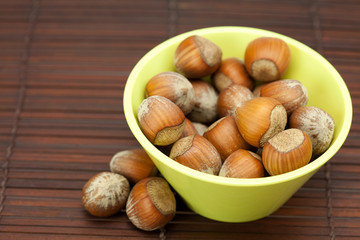 hazelnuts in a bowl on a bamboo mat