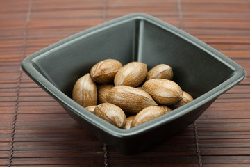 pecans in a bowl on a bamboo mat