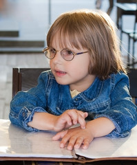 little girl sitting in cafe holding menu