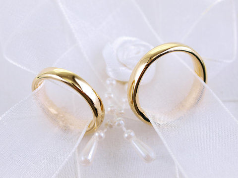 a pair of wedding rings on white lace