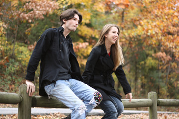 Couple jumping off wodden fence
