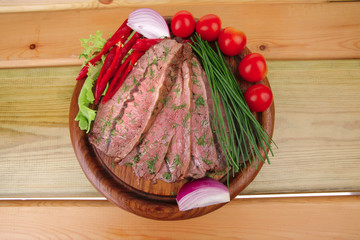 beef on wooden plate with peppers