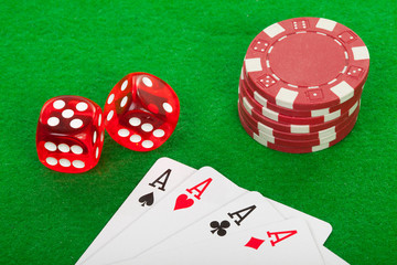 four aces playing cards and red dices on green background