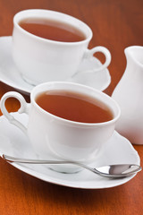 Black tea in mugs with saucers