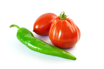 Two tomatoes and a green chili on a white background