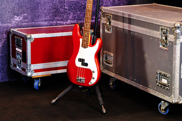 A red bass guitar and two cases on a stage