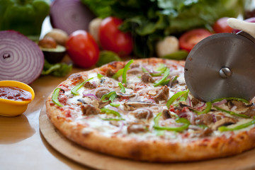 Whole vegetarian veggie Pizza, fresh baked, cut into slices with cutter roller