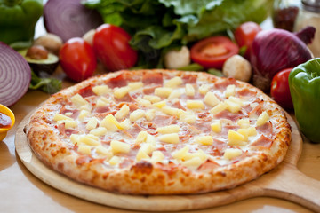 Whole hawaiian Pizza pineapple and ham, baked fresh out of the oven on wooden cutting board with ingredients