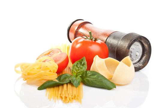 Pasta, tomato, salt and basil leaves on white background