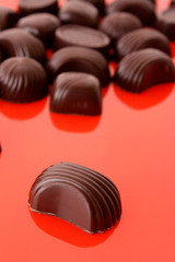 Assorted chocolate candies on red background