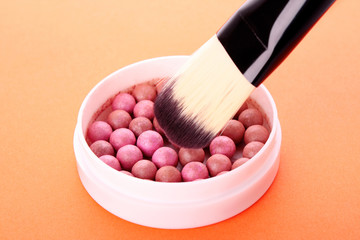 cosmetic brush and rouge  on the orange background