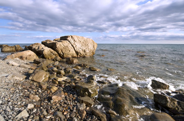 Sea coast with boulders and stones against a sky with clouds