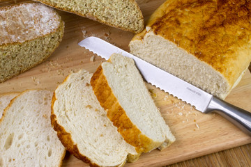 A loaf of homemade bread on a breadboard with a breadknife