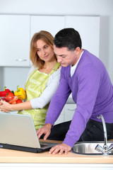 Couple in kitchen looking for cooking receipe