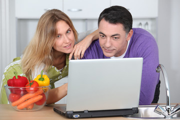 Couple in kitchen looking for cooking receipe