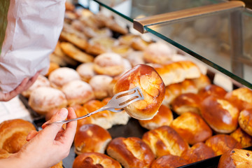 verkäuferin greift brötchen mit zange