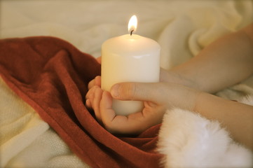 Kinderhände mit weißer Kerze