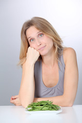 Unhappy woman in front of green beans