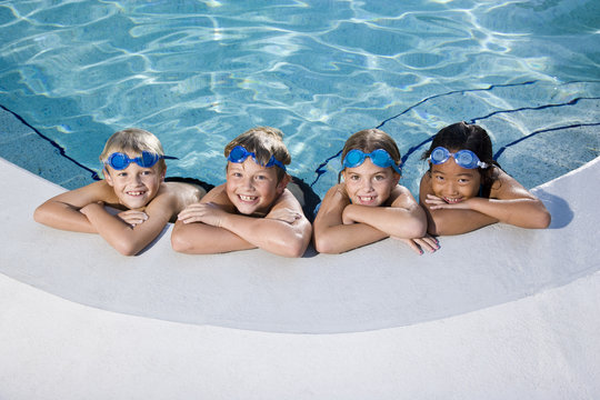 Children smiling at edge of swimming pool
