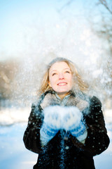 Happy friendly woman blowing snowflakes