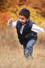 Toddler running up a hill in the fall