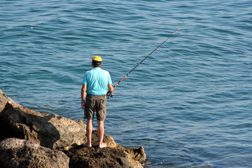 Fototapeta na wymiar samotny rybak na skałach