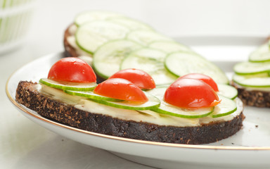 rye bread with sliced tomatoes, cucumbers and cheese on plate