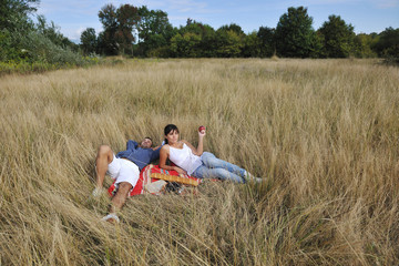 happy couple enjoying countryside picnic in long grass