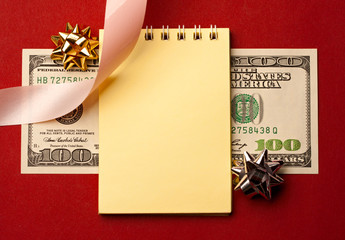 Notepad, dollar and decoration isolated on red