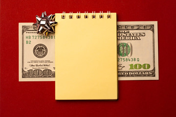 Notepad, dollar and bow isolated on red