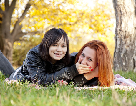 Two beautiful girlfriends at the autumn park near tree.