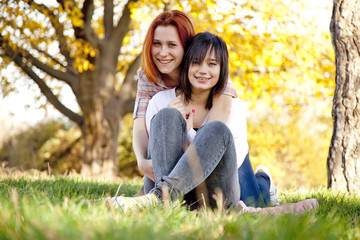 Two beautiful girlfriends at the autumn park near tree.