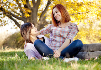 Naklejka na ściany i meble Two beautiful girlfriends at the autumn park near tree.