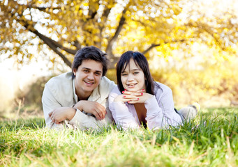 Couple lie at green grass in the park.