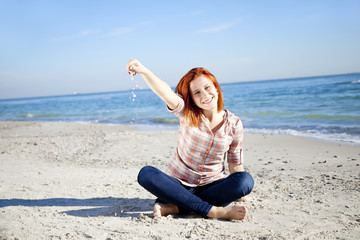 Fototapeta na wymiar Happy red-haired girl at the beach.
