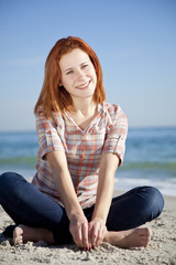Fototapeta na wymiar Happy red-haired girl at the beach.