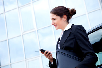 Business woman outside with mobile phone, smiling